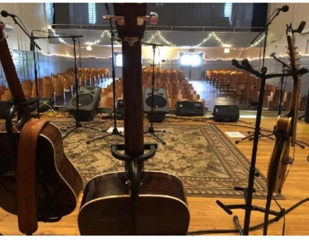 Music at Union Mills Learning Center. Stage view of an auditorium. There are several instruments also in view.