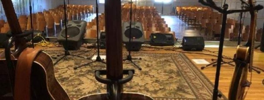 Music at Union Mills Learning Center. Stage view of an auditorium. There are several instruments also in view.