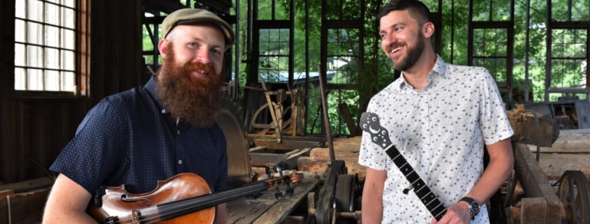 Josh Goforth holding banjo & Bryan McDowell holding fiddle
