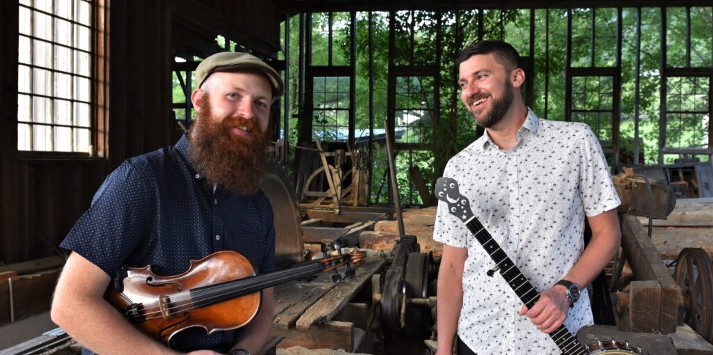 Josh Goforth holding banjo & Bryan McDowell holding fiddle