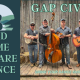 An old-time music band of 4 musicians stands in blue outfits with their instruments.