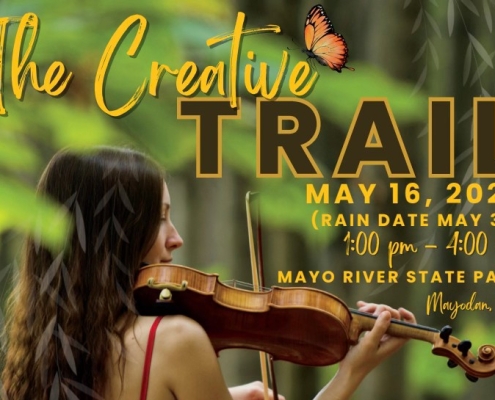 The Creative Trail from Rockingham Arts Council. A young woman in a red dress stands in a forest while playing a fiddle.