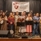 JAM students from the Folk School stand on stage with their instruments.